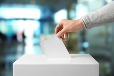 Image of Man putting his vote into ballot box indoors, closeup