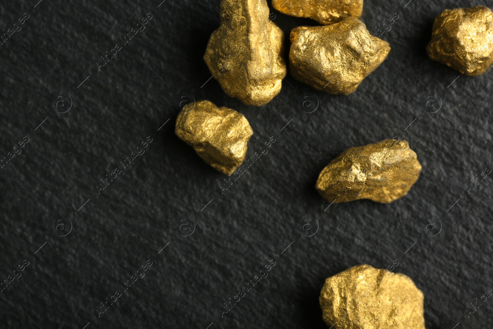 Photo of Shiny gold nuggets on grey textured surface, flat lay. Space for text