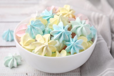 Photo of Tasty meringue cookies in bowl on white wooden table