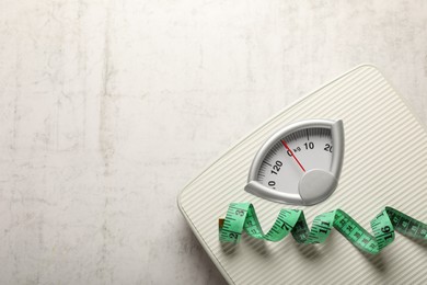 Photo of Weigh scales and measuring tape on white textured background, top view with space for text. Overweight concept