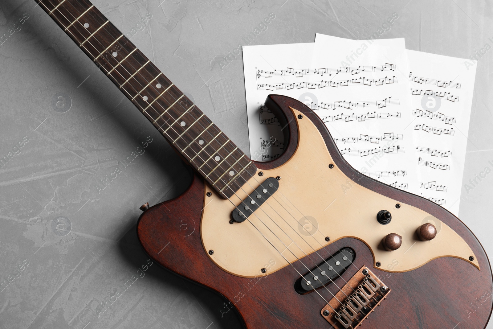 Photo of Modern electric guitar and music sheets on color background, top view