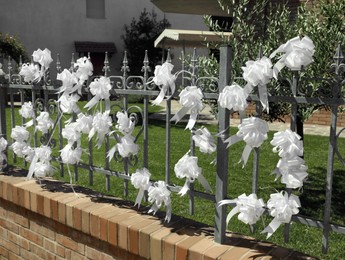 Photo of Metal fence with white bows on sunny day