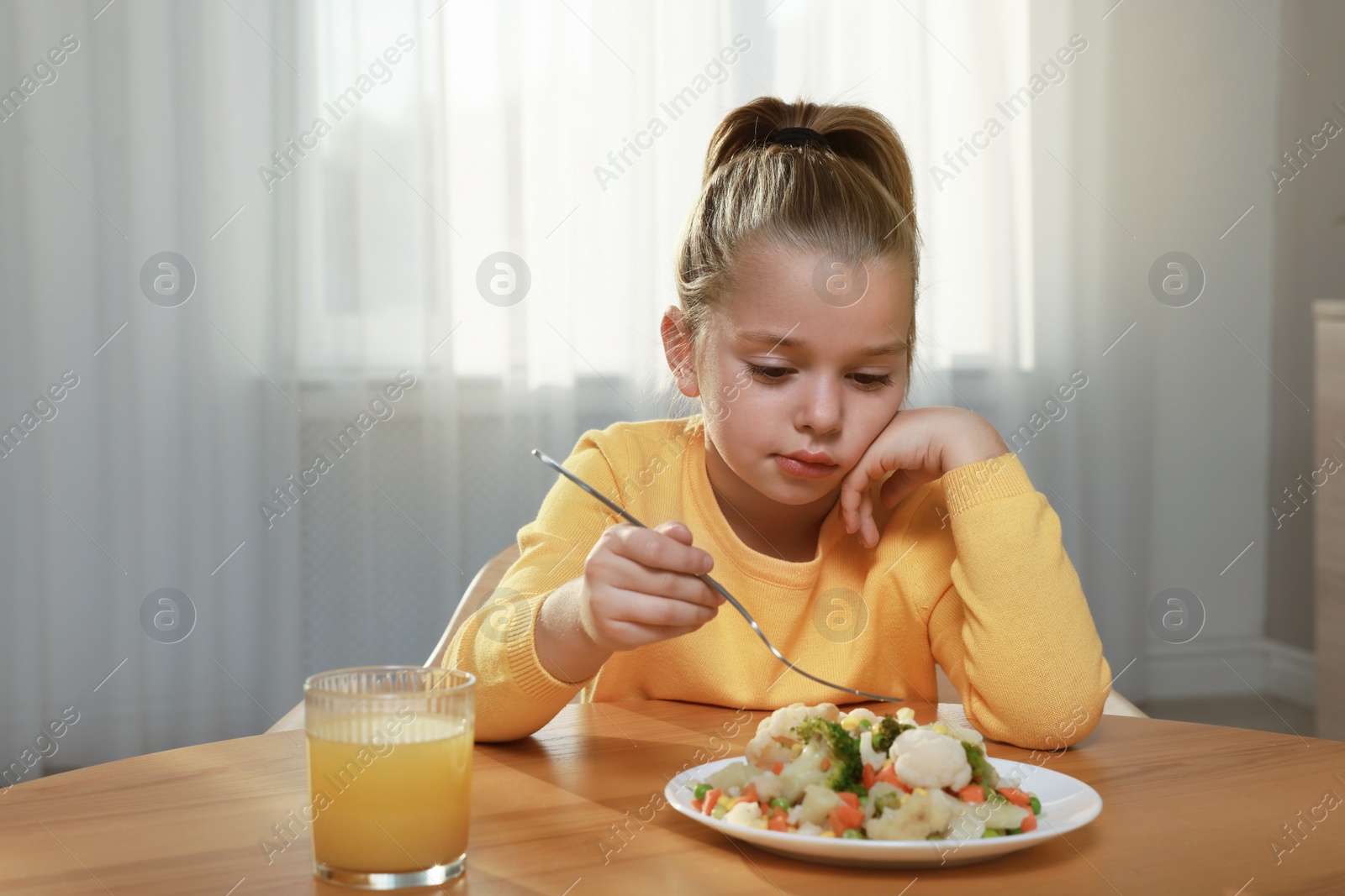 Photo of Cute little girl refusing to eat vegetable salad at home