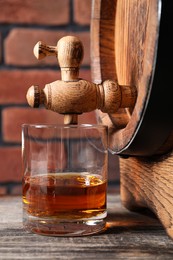 Photo of Glass of whiskey and wooden barrel on table, closeup