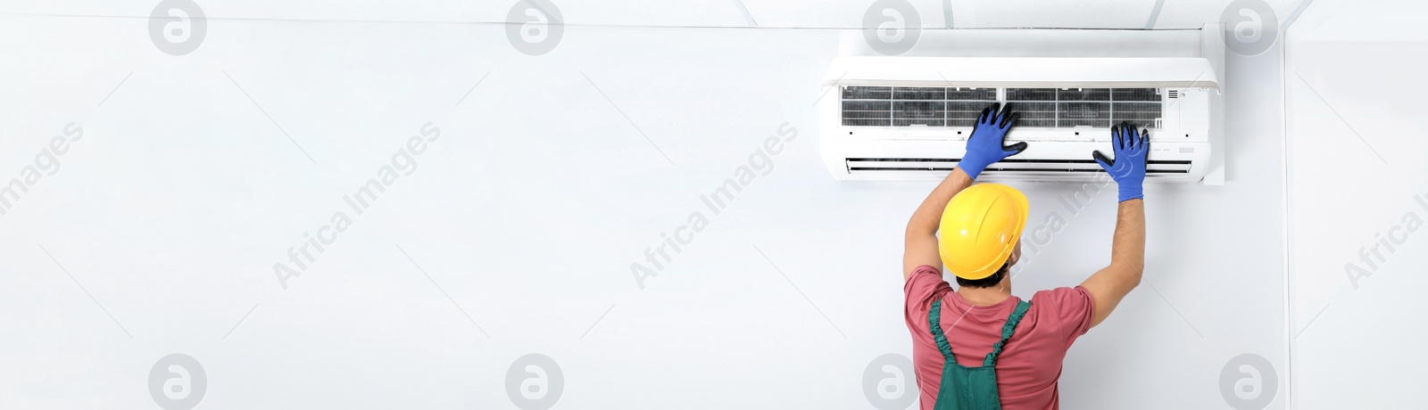 Image of Male technician checking air conditioner indoors, space for text. Banner design