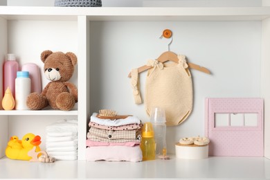 Baby clothes, toys and accessories on white rack