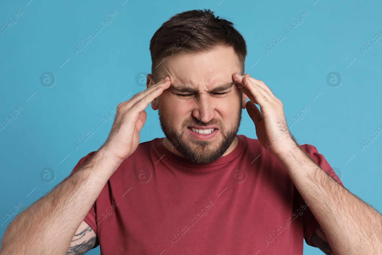 Photo of Man suffering from migraine on light blue background