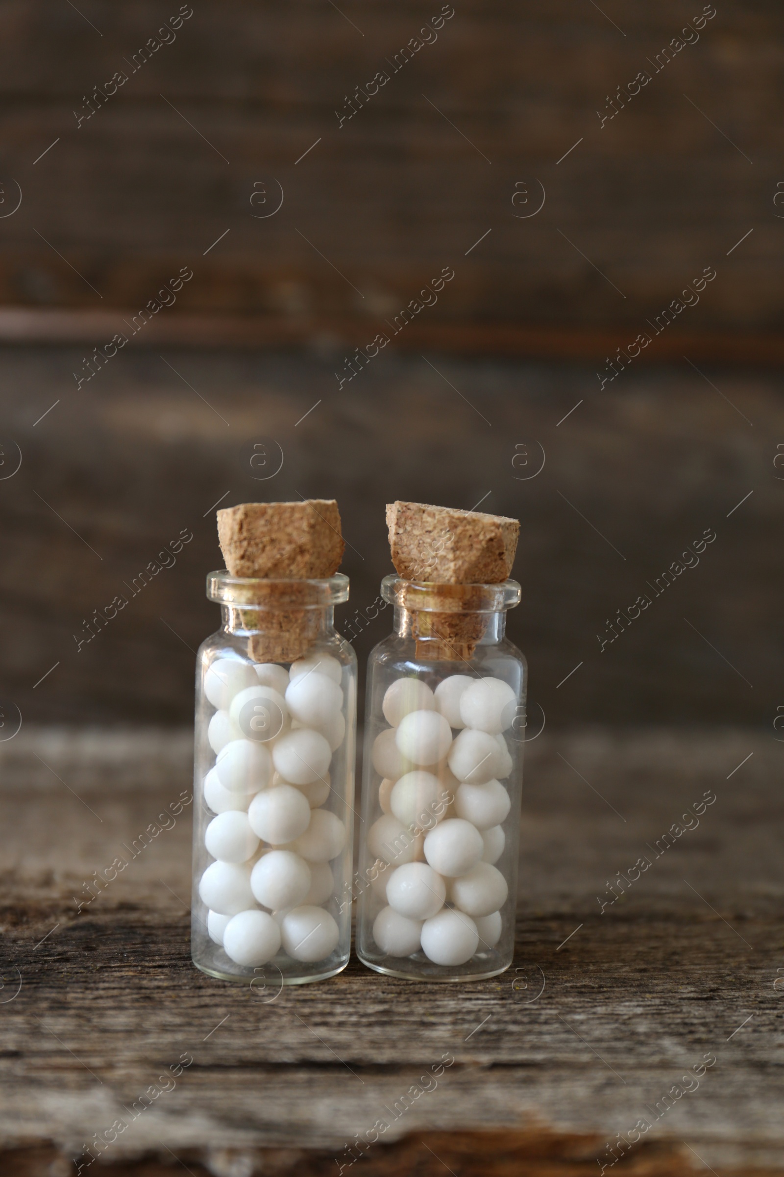 Photo of Bottles with homeopathic remedy on wooden table, closeup. Space for text