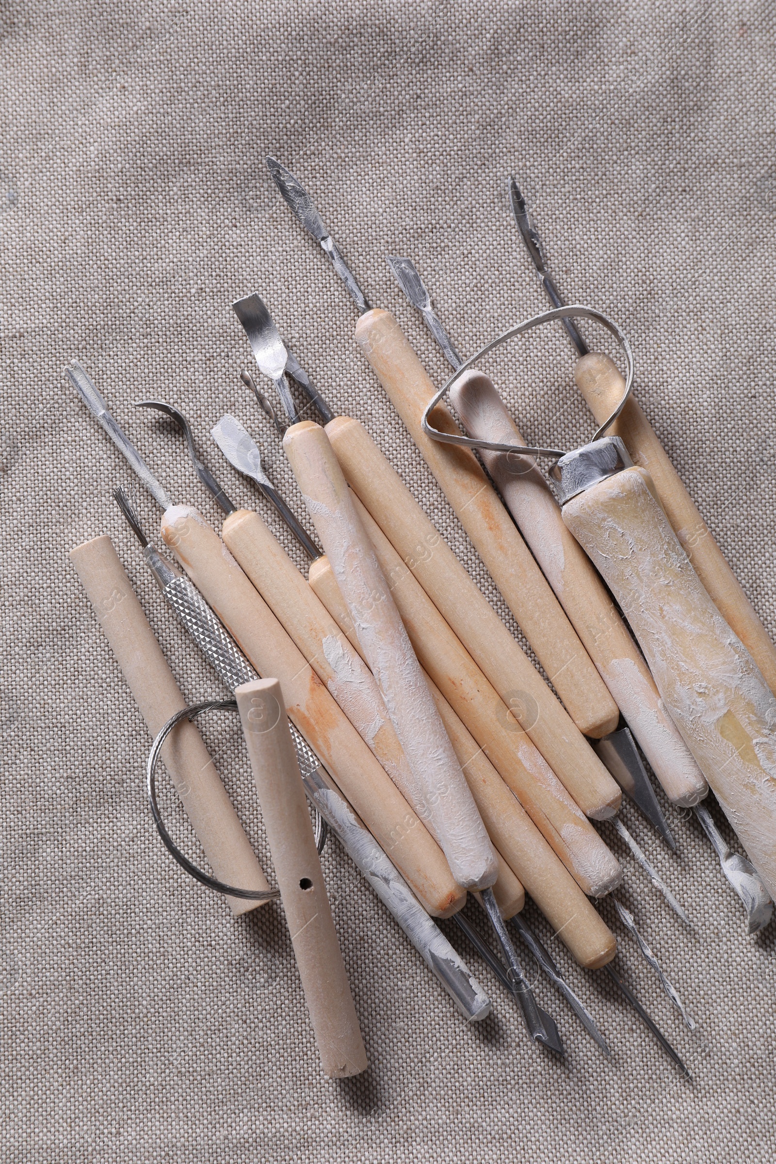 Photo of Set of different clay crafting tools on grey fabric, top view