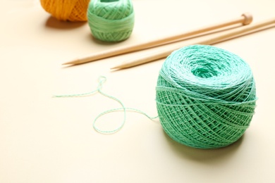 Photo of Clew of threads and knitting needles on color background, space for text. Sewing stuff