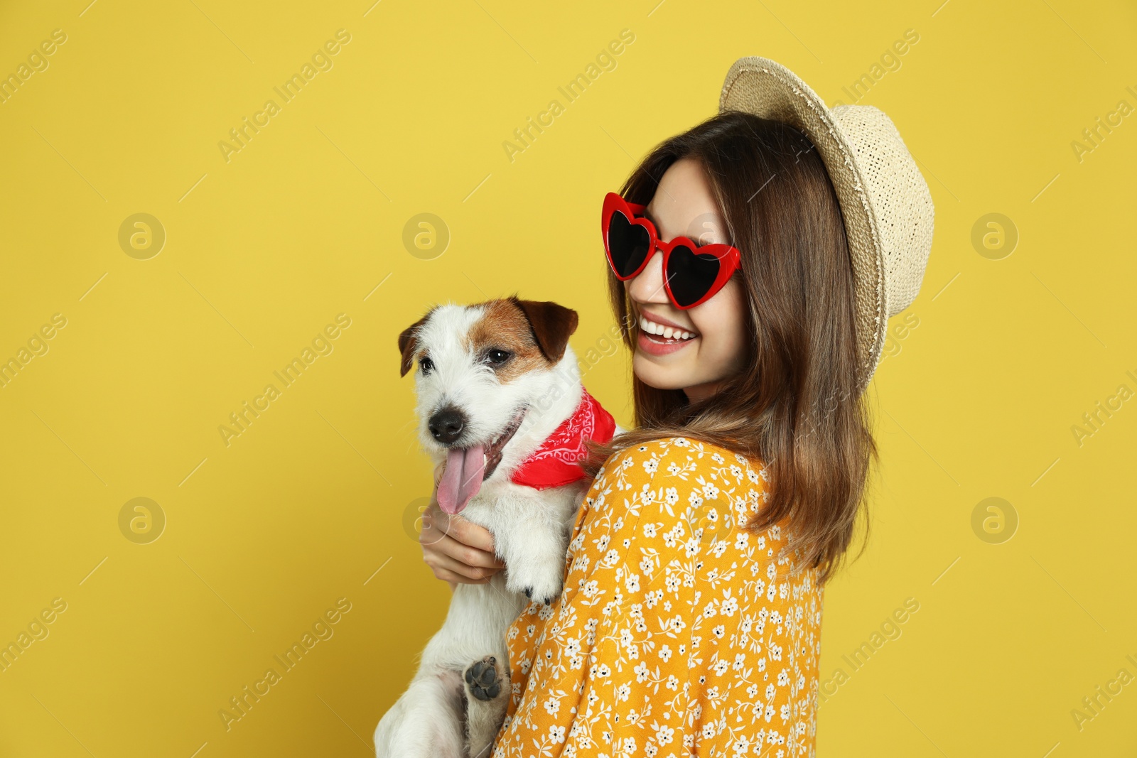 Photo of Young woman with her cute Jack Russell Terrier on yellow background. Lovely pet