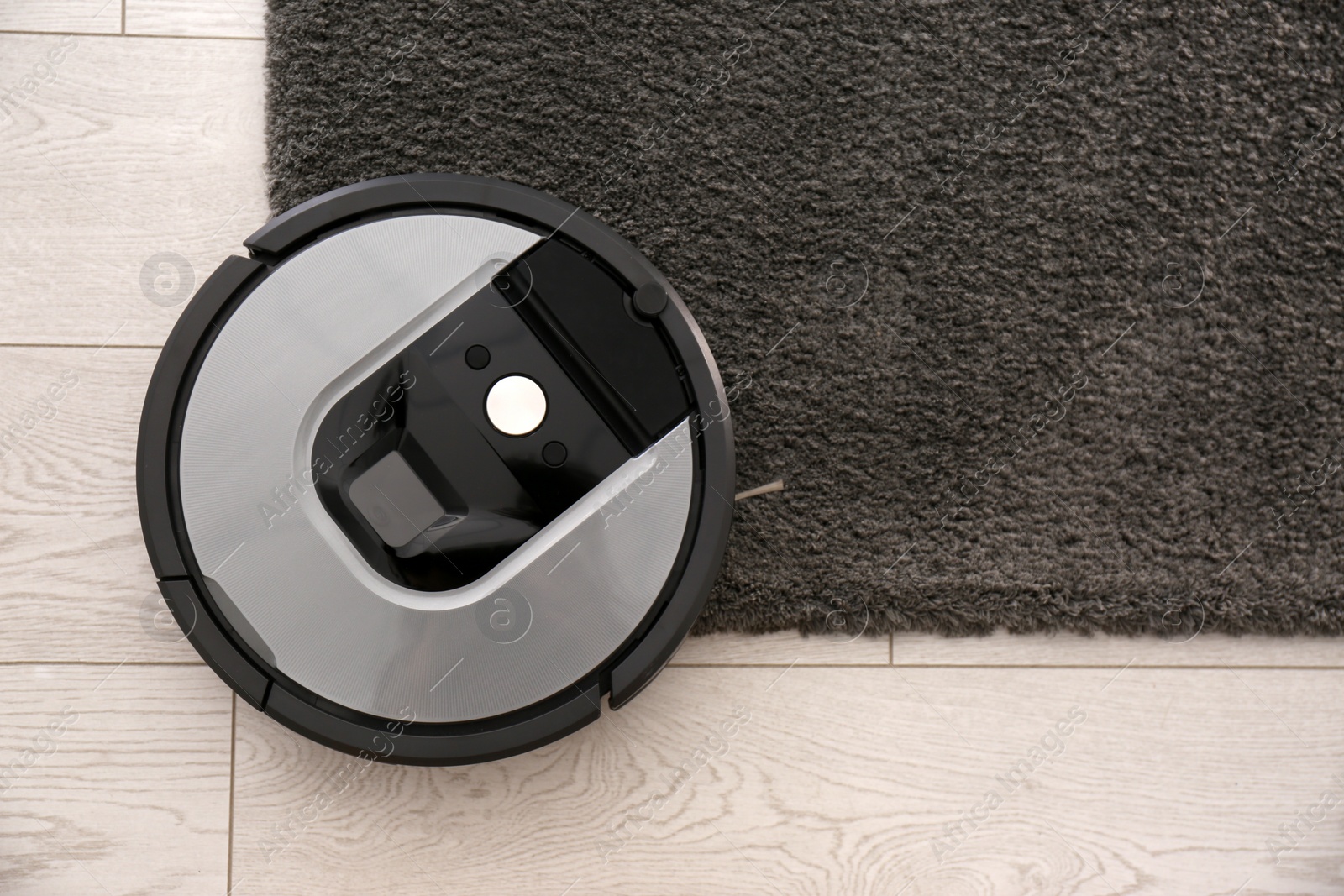 Photo of Modern robotic vacuum cleaner on dark carpet, top view. Space for text