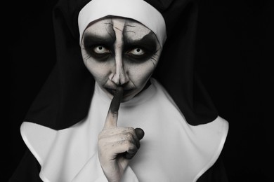 Photo of Portrait of scary devilish nun on black background. Halloween party look