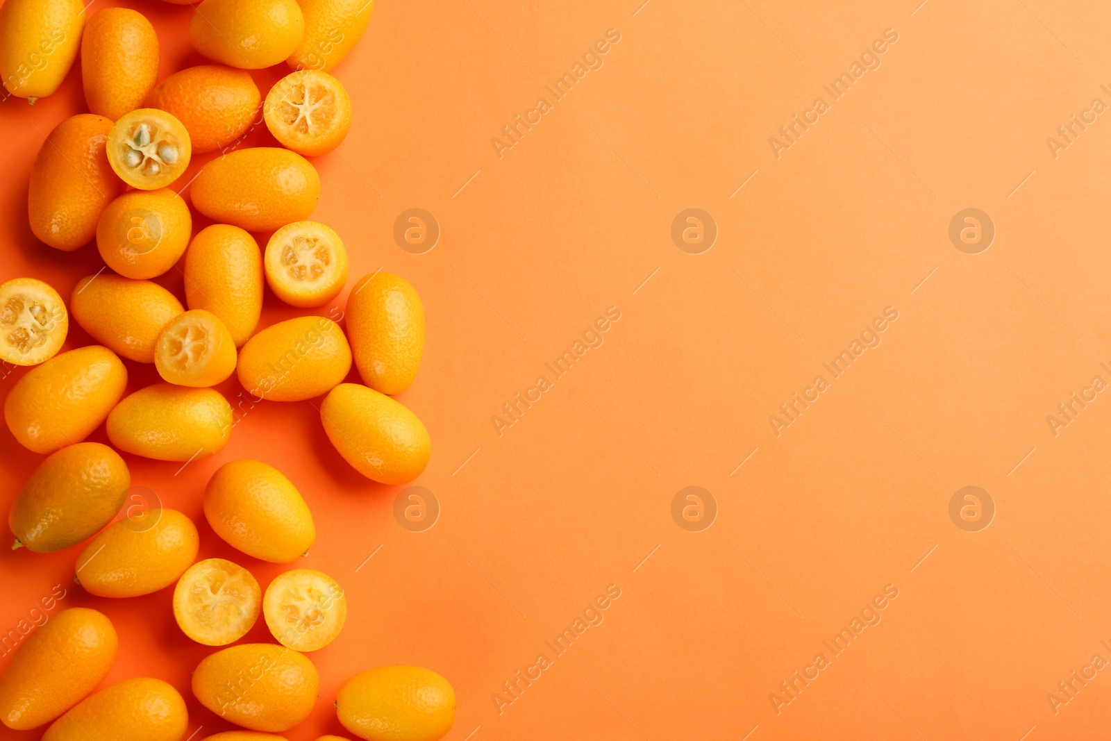 Photo of Fresh ripe kumquats on orange background, flat lay. Space for text