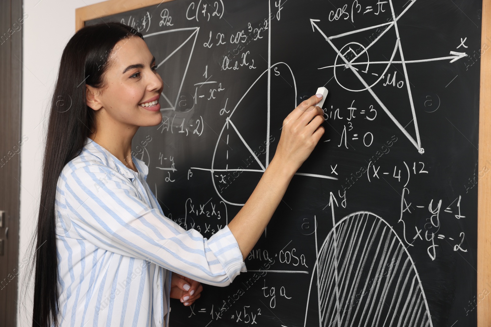 Photo of Happy teacher explaining mathematics at chalkboard in classroom