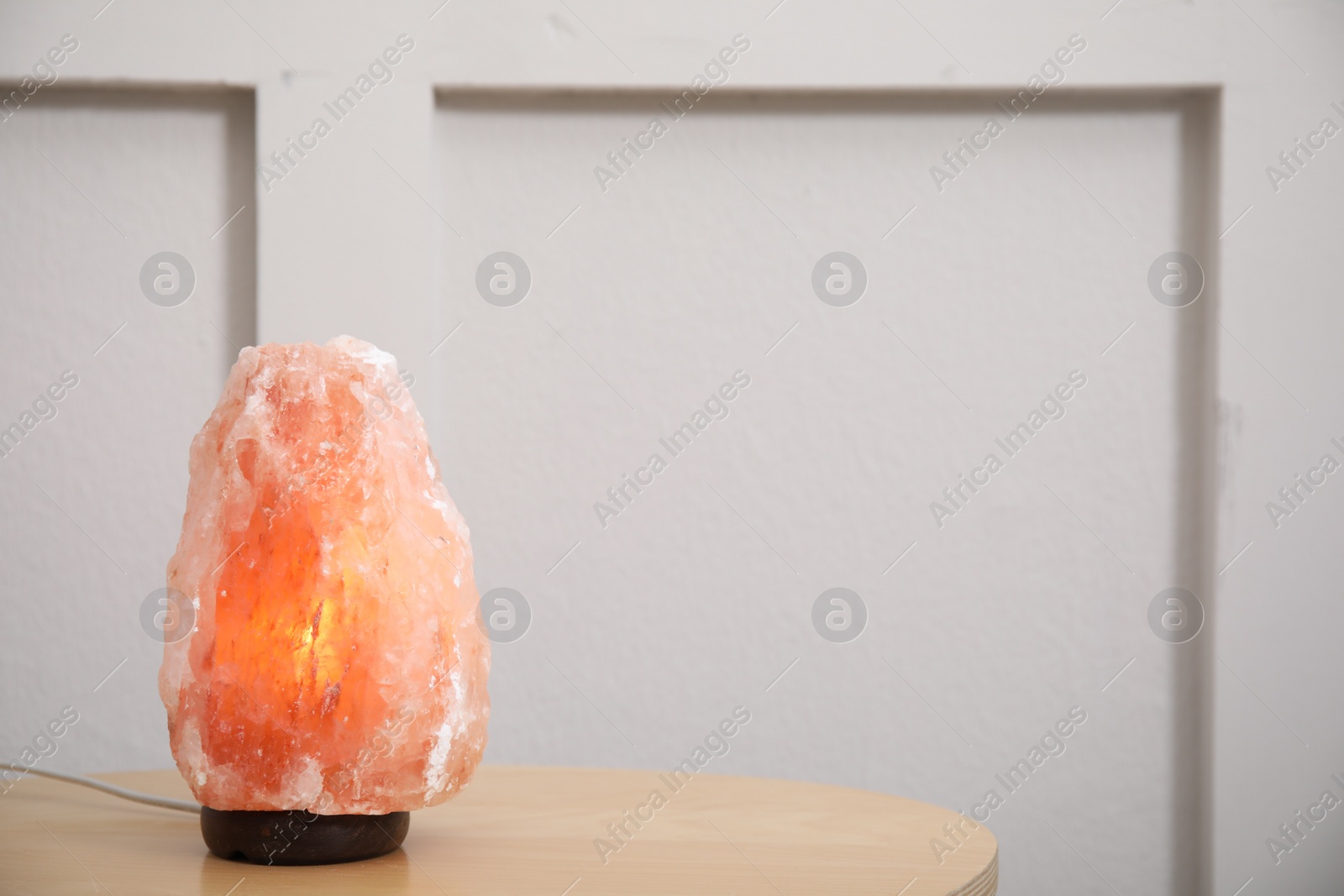 Photo of Himalayan salt lamp on wooden table indoors. Space for text