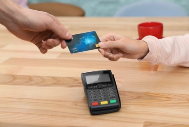 Photo of Client using credit card machine for non cash payment at table, closeup