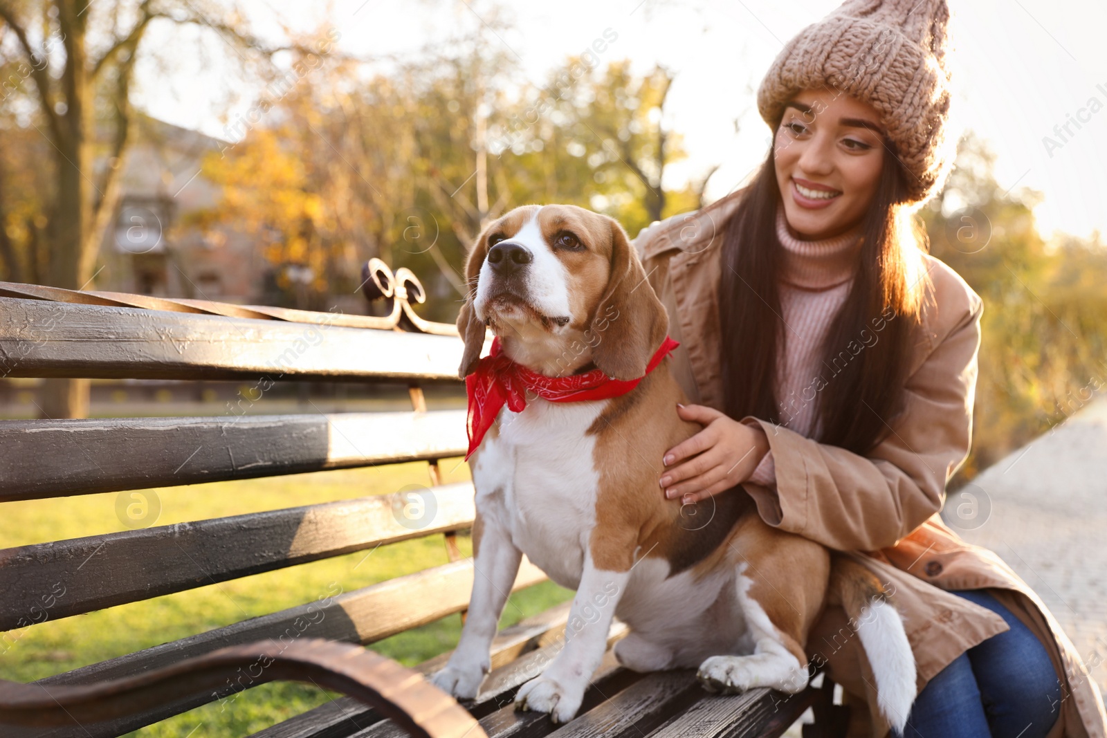 Photo of Woman walking her cute Beagle dog in autumn park