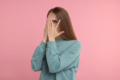 Photo of Embarrassed woman covering face with hands on pink background