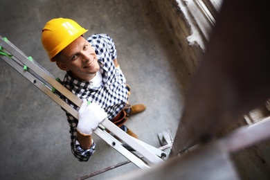 Photo of Professional constructor with ladder in old building, above view