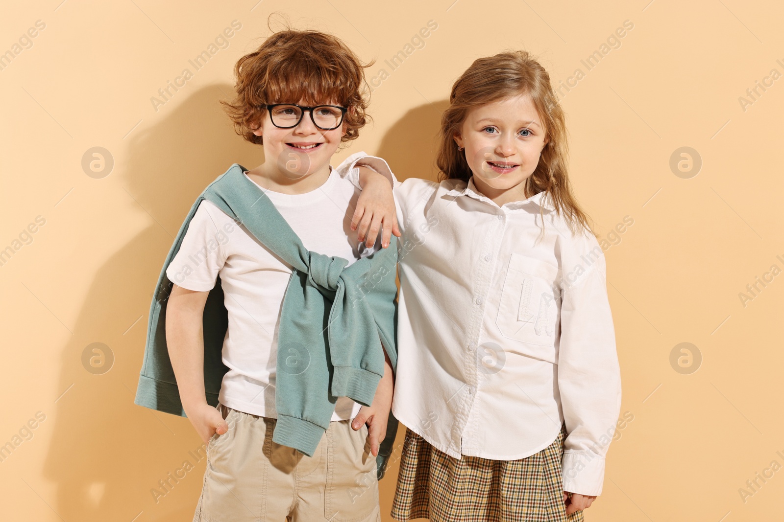 Photo of Fashion concept. Stylish children on pale orange background