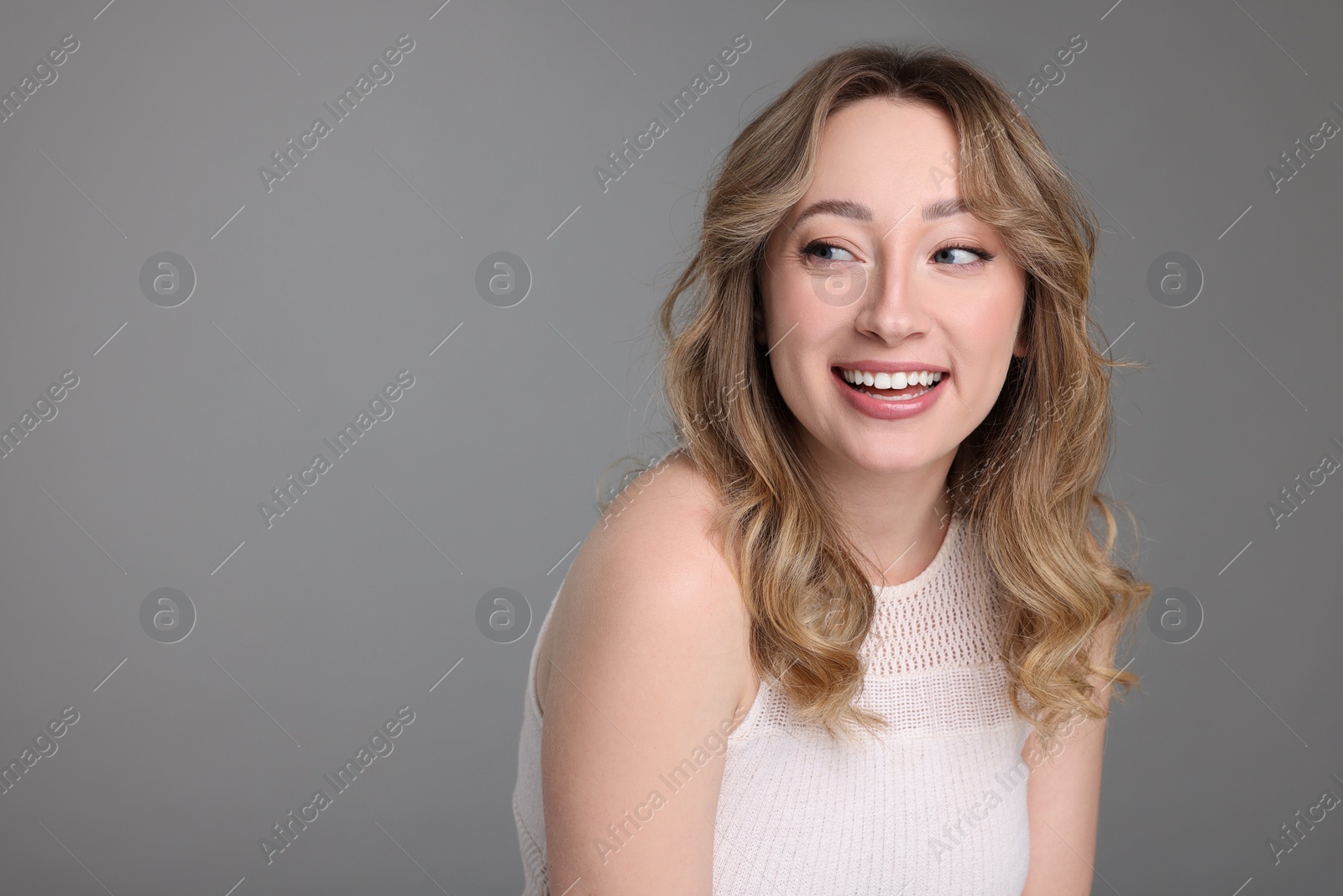 Photo of Portrait of smiling woman on grey background. Space for text