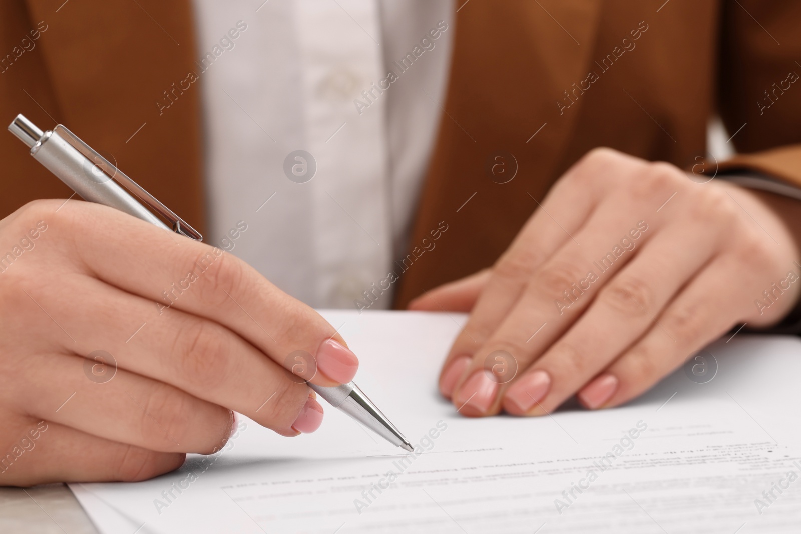 Photo of Woman signing document at table, closeup view