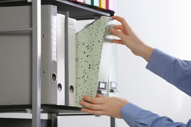 Photo of Woman taking folder with documents from shelf on white background, closeup