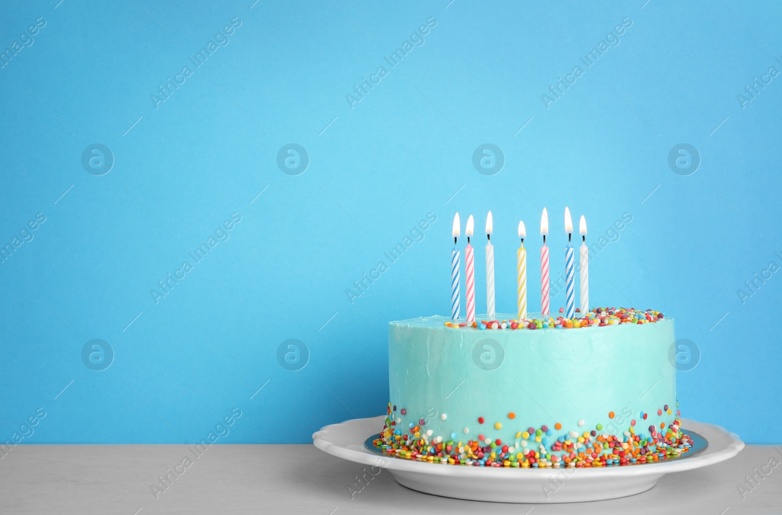 Photo of Fresh delicious birthday cake with candles on table against color background. Space for text