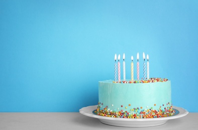 Photo of Fresh delicious birthday cake with candles on table against color background. Space for text