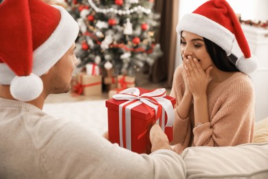 Happy young couple with Christmas gift at home