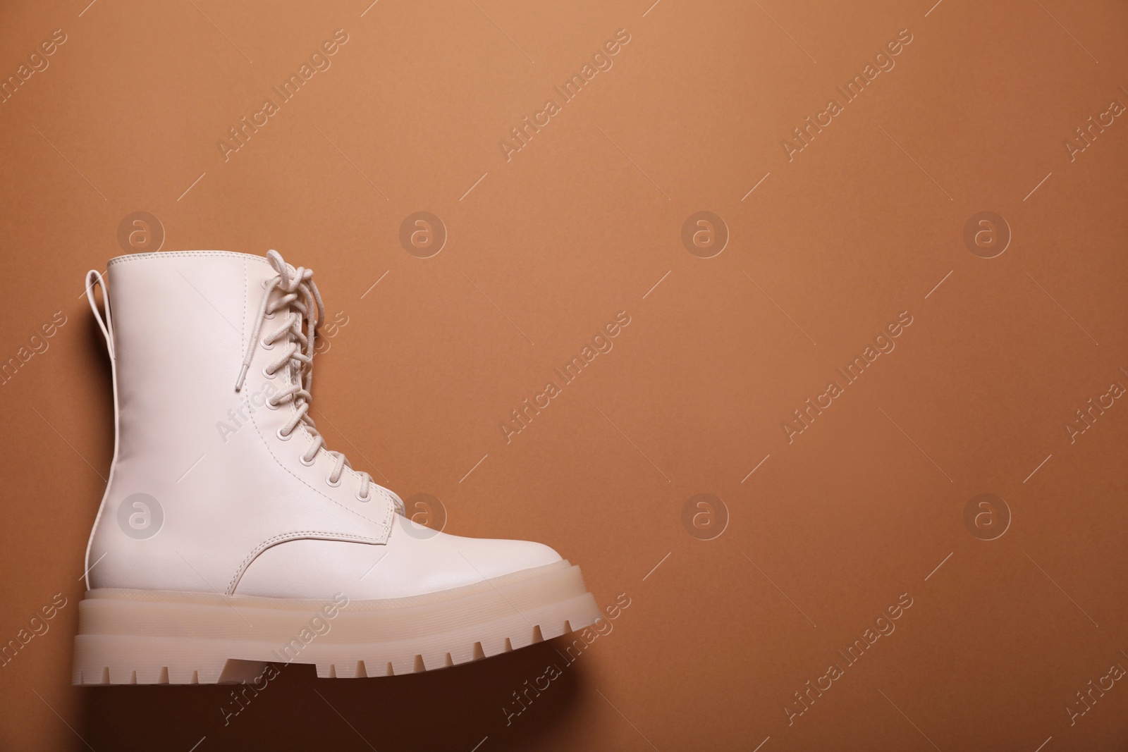 Photo of Stylish leather shoe on light brown background, top view. Space for text