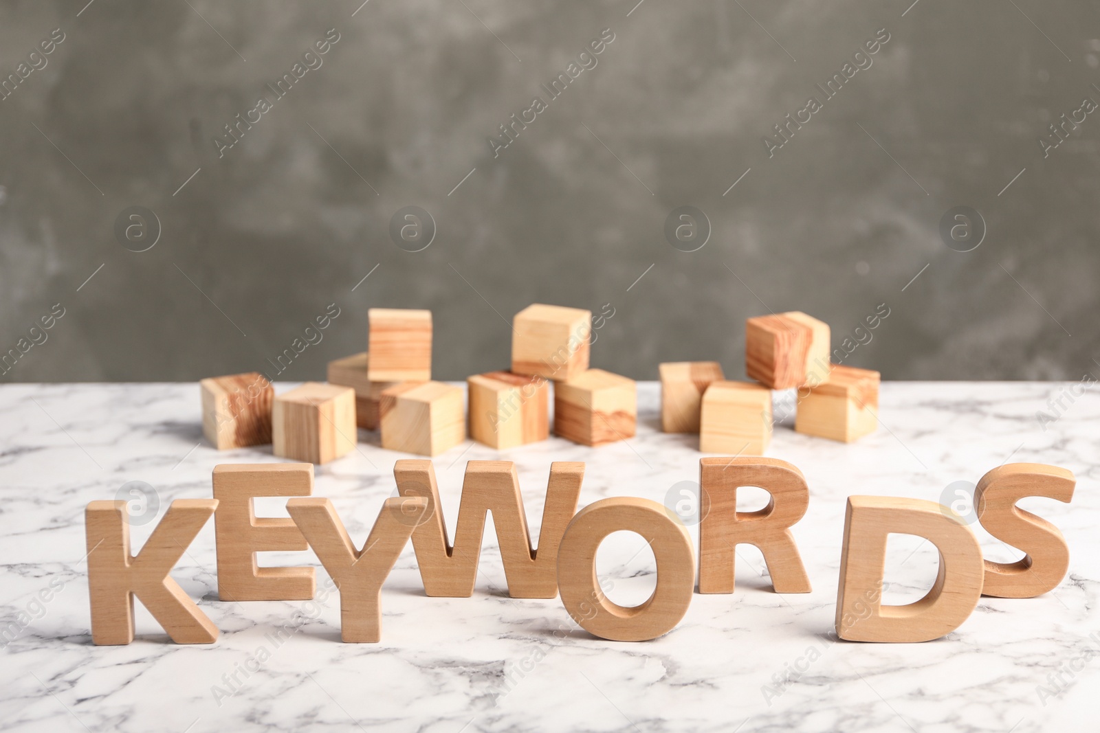 Photo of Word KEYWORDS made of wooden letters on white marble table