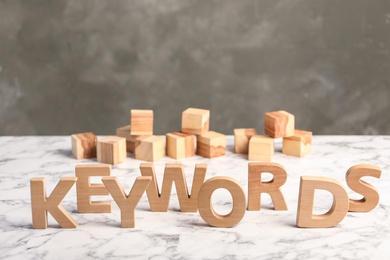 Photo of Word KEYWORDS made of wooden letters on white marble table