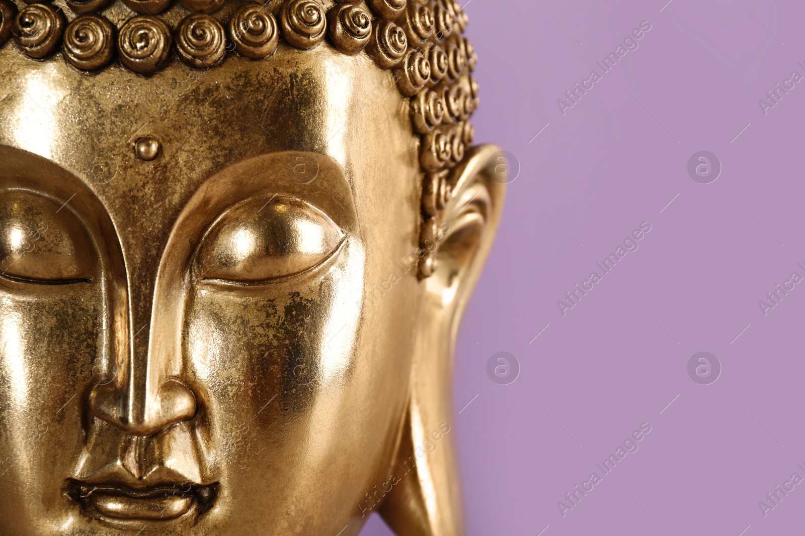 Photo of Beautiful golden Buddha sculpture on violet background, closeup. Space for text