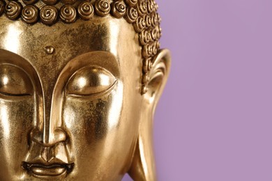 Photo of Beautiful golden Buddha sculpture on violet background, closeup. Space for text