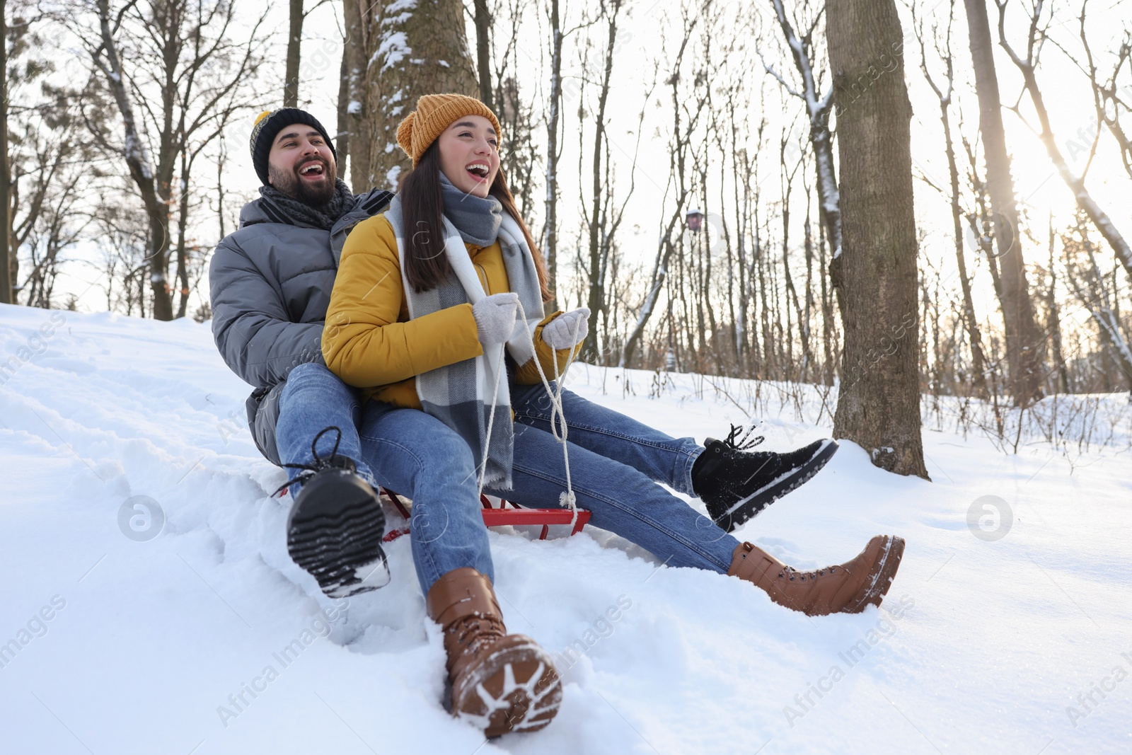 Photo of Happy young couple sledding outdoors on winter day