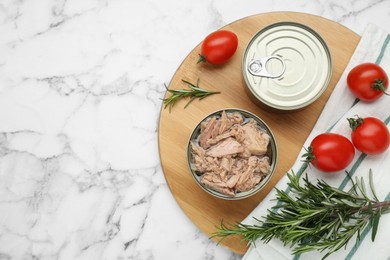 Photo of Tin cans with canned tuna and products on white marble table, flat lay. Space for text