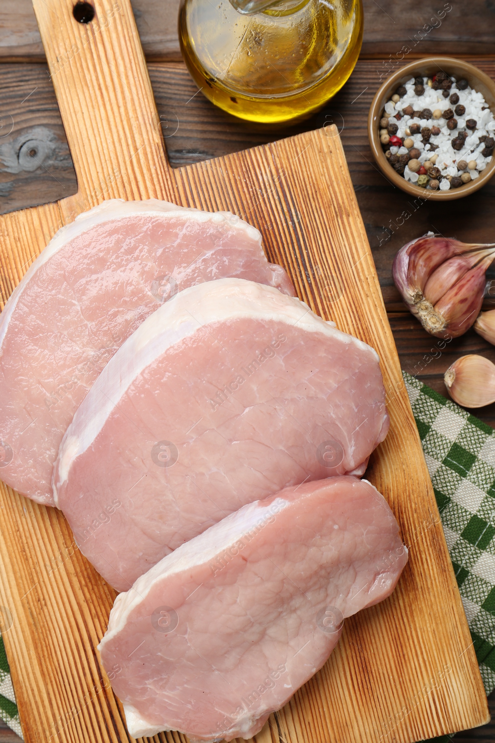 Photo of Pieces of raw pork meat, oil and spices on wooden table, flat lay