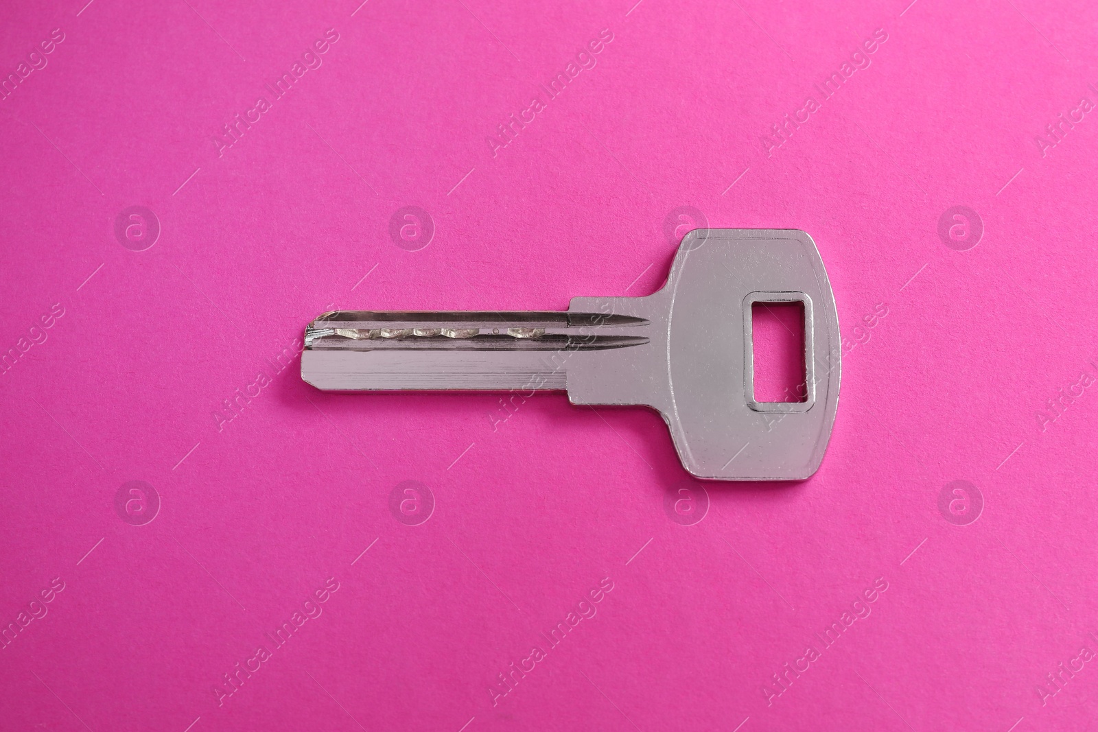 Photo of One key on pink background, top view