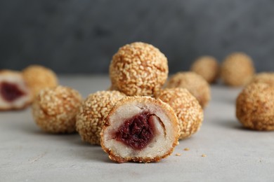Photo of Delicious sesame balls with red bean paste on light grey table, closeup