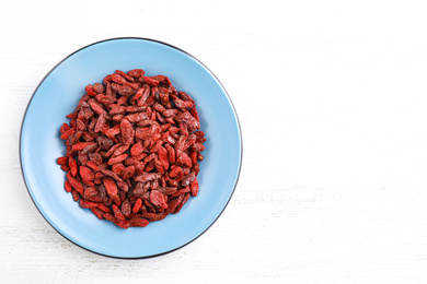 Photo of Dry goji berries on white wooden table, top view. Space for text