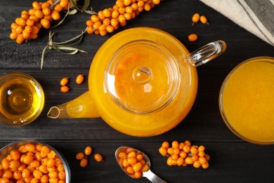 Photo of Flat lay composition of delicious sea buckthorn tea on black wooden table