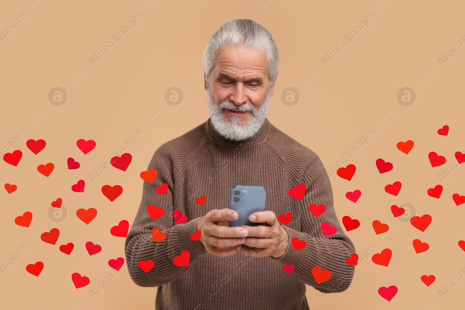 Image of Long distance love. Man chatting with sweetheart via smartphone on dark beige background. Hearts flying out of device and swirling around him