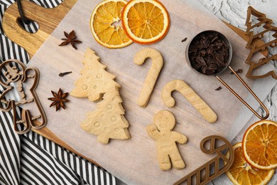 Photo of Christmas treat. Flat lay composition with cookie cutters and baked biscuits on white textured table