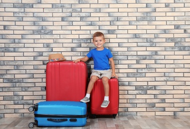 Photo of Little boy with suitcases near brick wall. Space for text