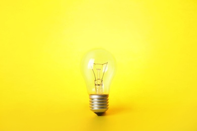 Photo of New incandescent lamp bulb on yellow background