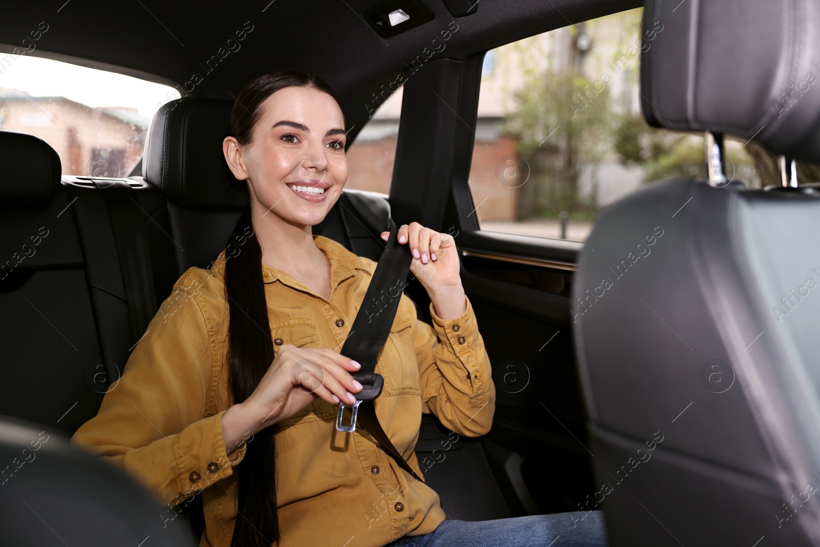 Photo of Woman fastening safety seat belt inside modern car