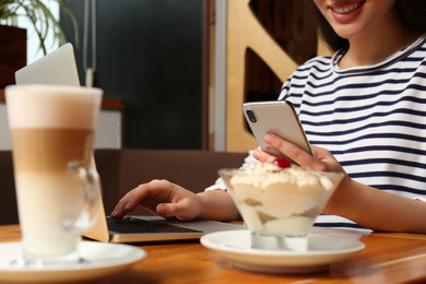 Photo of Young blogger with laptop and smartphone in cafe, closeup