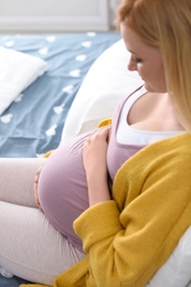 Young pregnant woman resting on bed at home